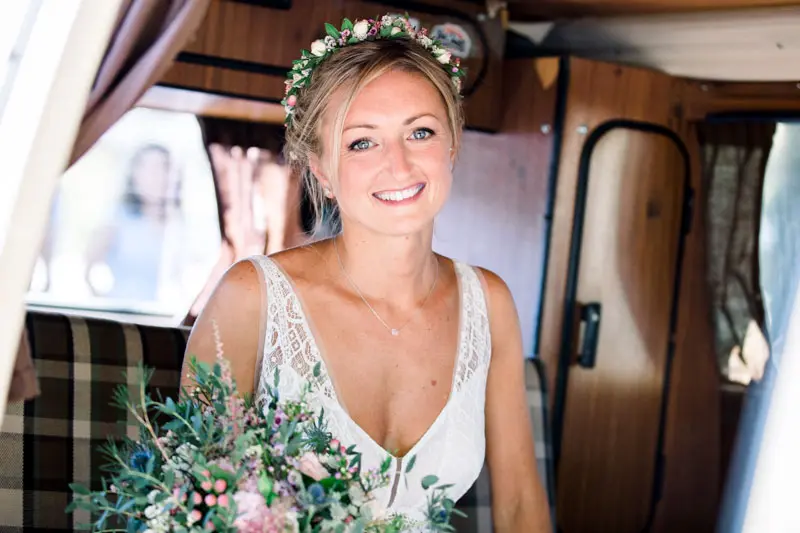 The bride smiling inside a vintage van, bouquet in hand, before the church