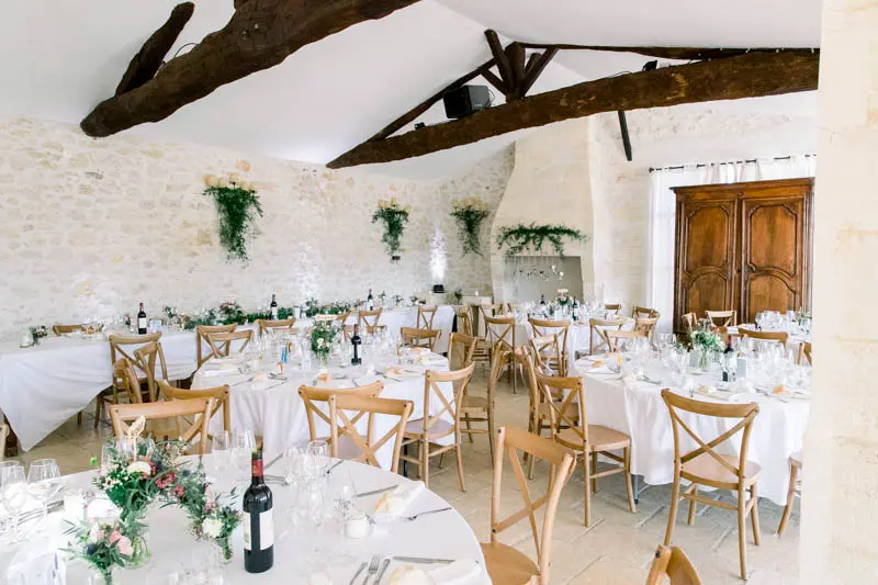 Reception hall with exposed beams and set tables at Château Isabeau de Naujan