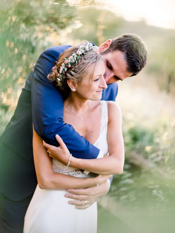 The newlyweds embracing at sunset, vertical frame, in the tall grass of the estate