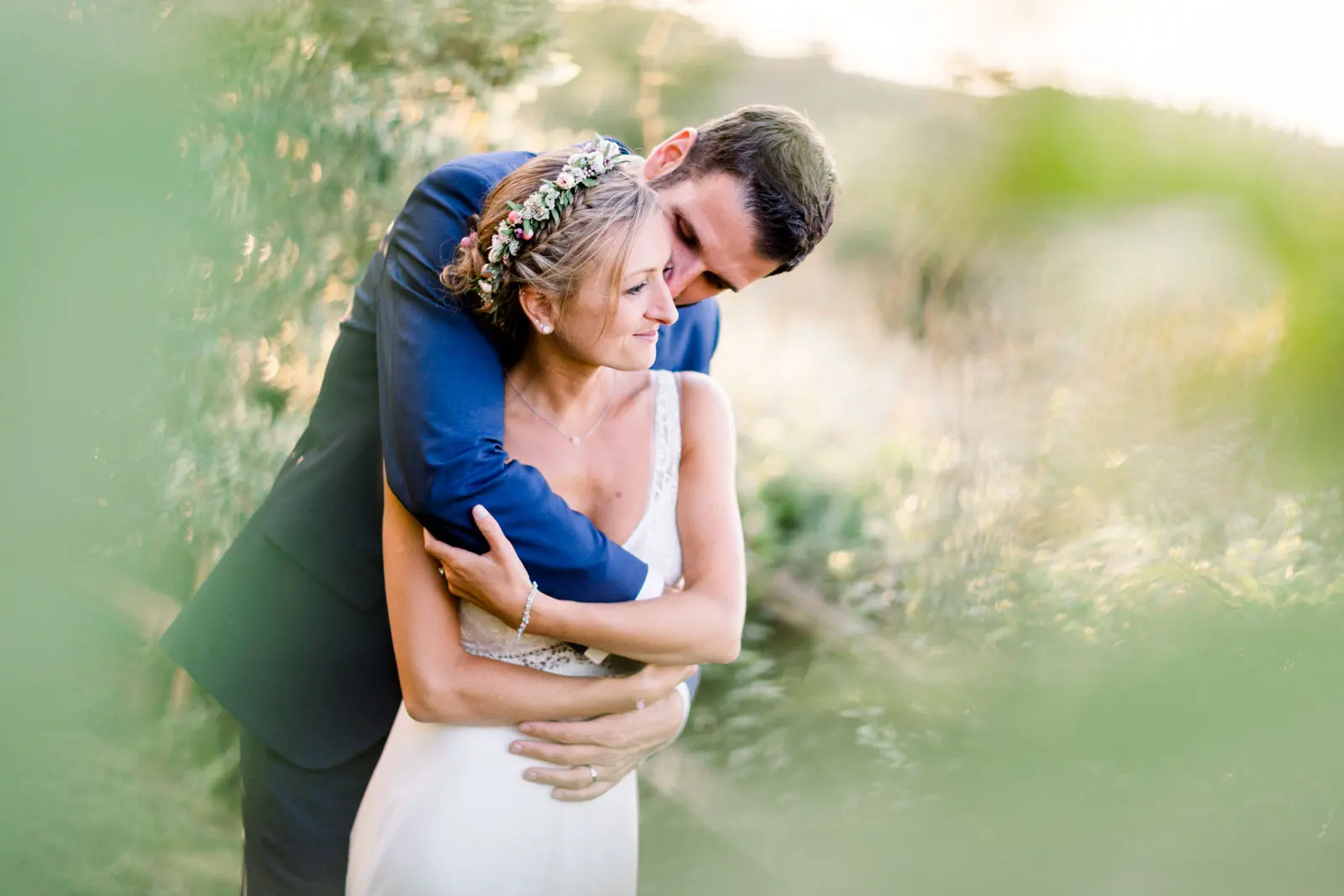 Flavie and Guillaume embracing in tall grass at Château Isabeau de Naujan