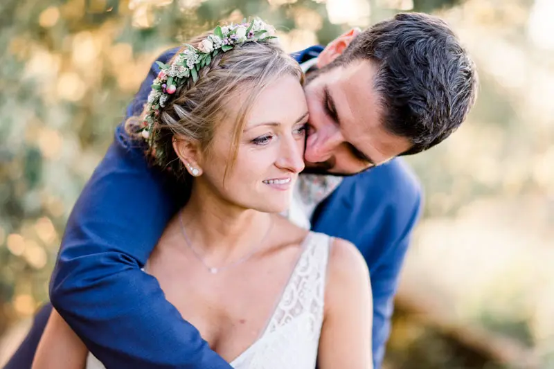 The groom tenderly kisses the bride's cheek in evening light