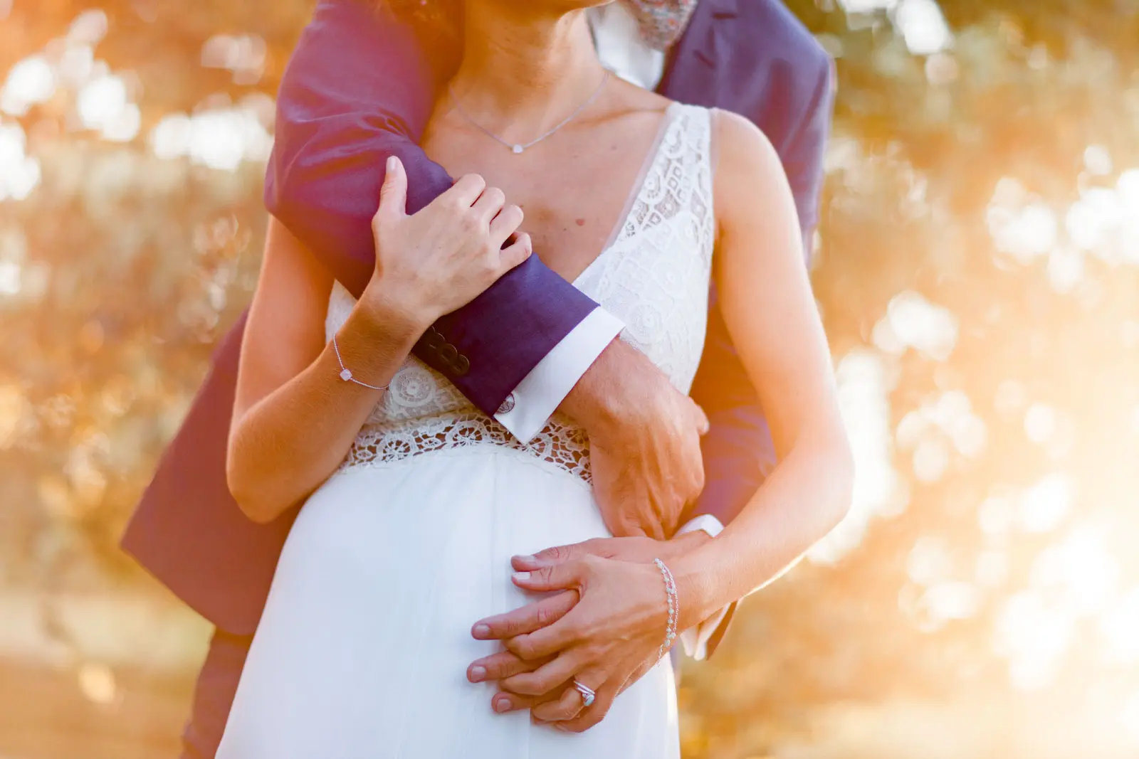 The groom's hands wrapped around the bride's waist in golden evening light