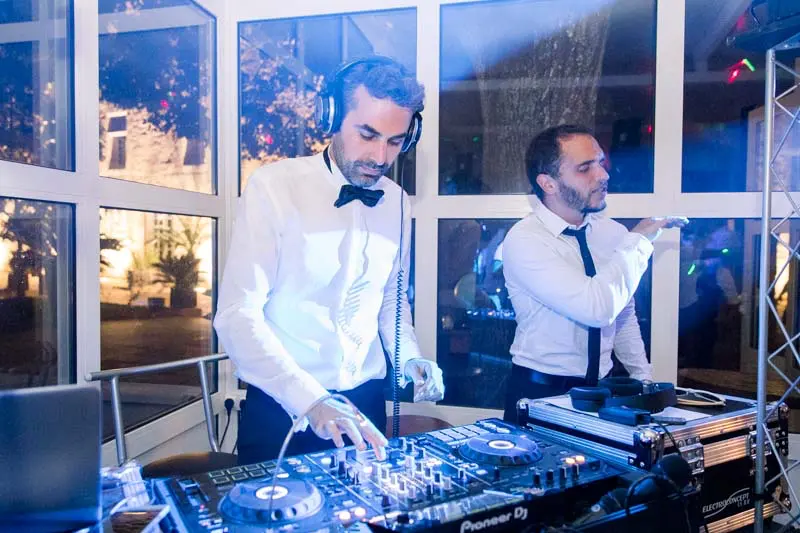 The DJs at the decks in front of the glass windows during the wedding party