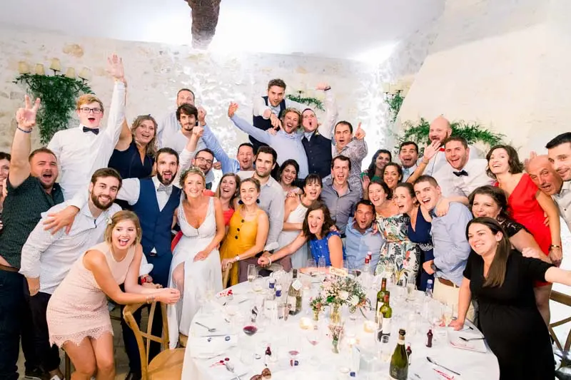 Group photo of guests celebrating around the tables during the evening party