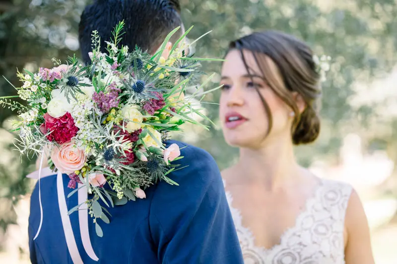 Floride resting her colourful bouquet on Benjamin's shoulder at the first look