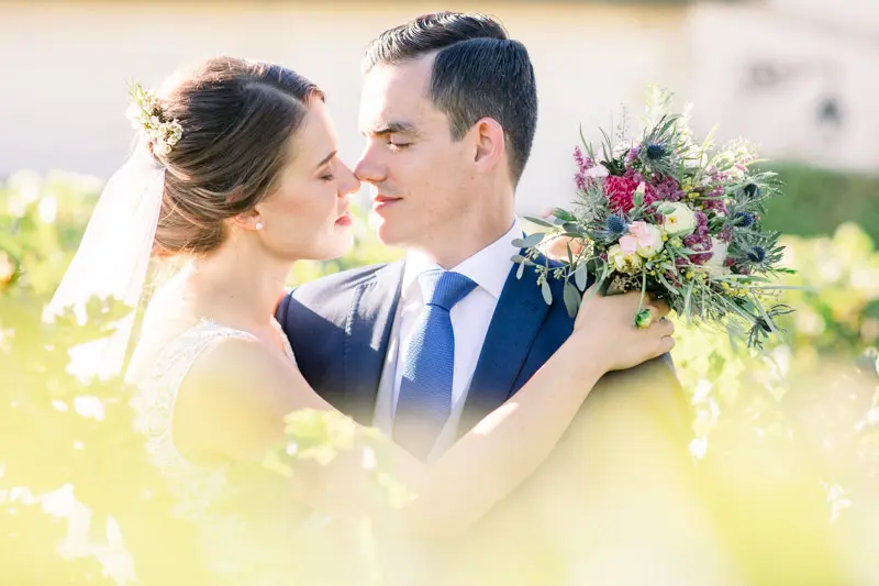 Bride and groom gazing tenderly at each other in golden light, bouquet raised