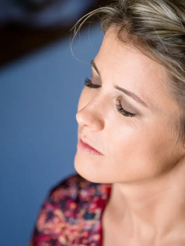 The bride with eyes closed during her makeup session, in a floral kimono