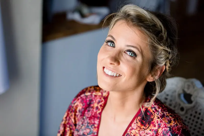 The bride smiling and looking up during her makeup