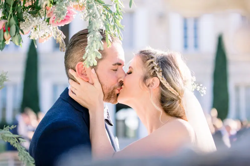 The couple's first kiss beneath the floral ceremony arch