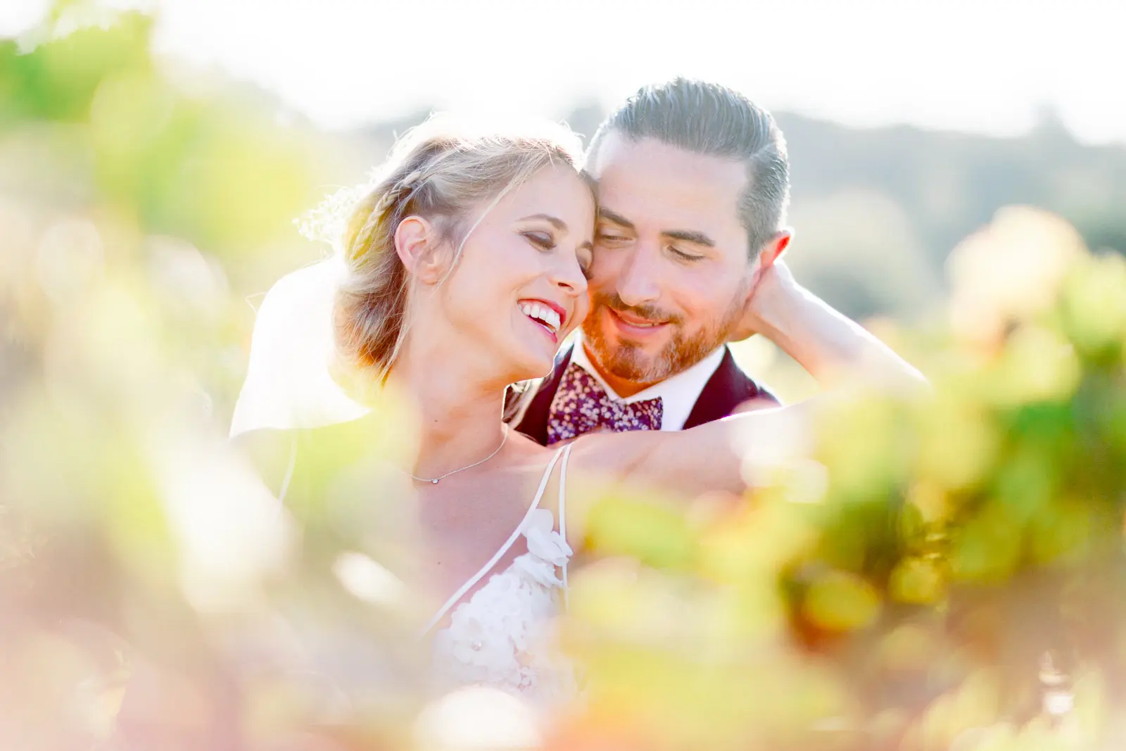 The bride and groom laughing in an embrace in the vines of Château de Garde, Moulon
