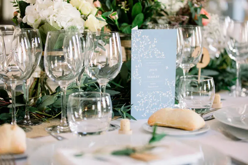 Table detail with a pale blue card, bread rolls and white flowers