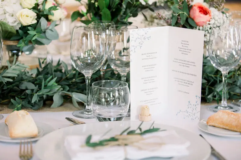 Table set with a menu card, stemmed glasses and a eucalyptus garland