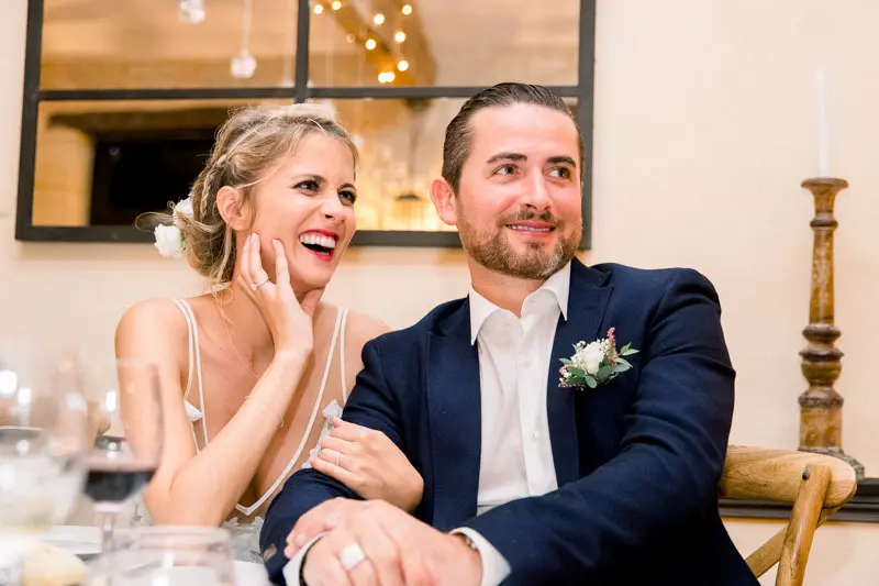 The bride and groom laughing at their table during the evening