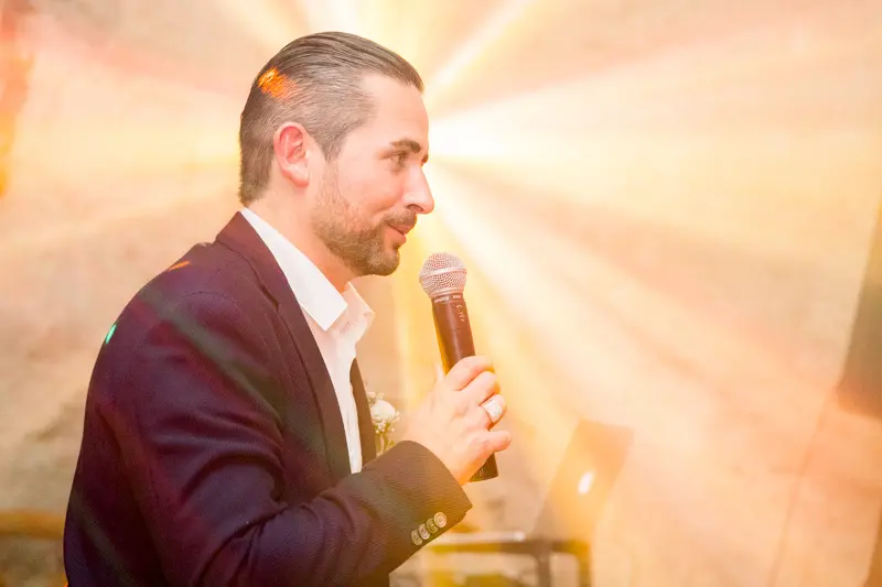 The groom giving his speech into the microphone in golden light