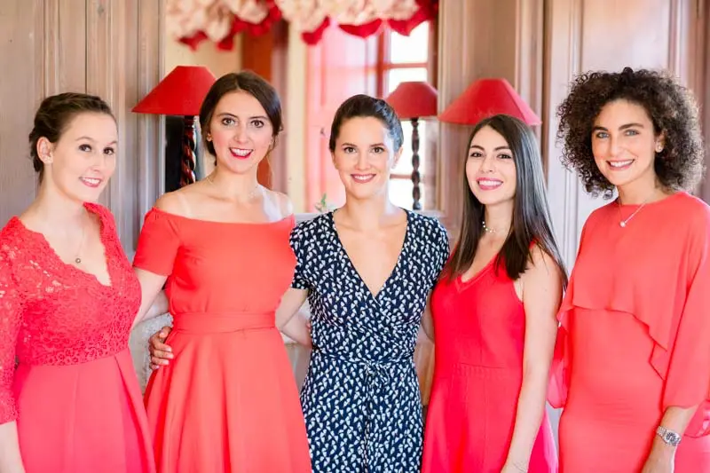 Bridesmaids in red and coral dresses while getting ready