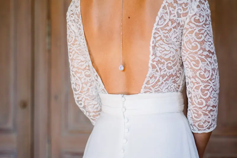 Lace open back of the wedding gown adorned with a back necklace