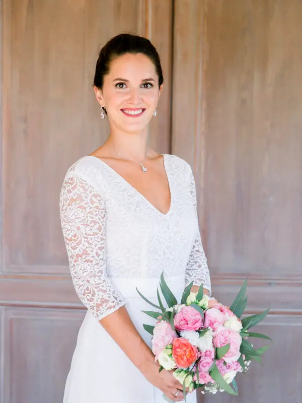Smiling bride holding a bouquet of pink roses and peonies