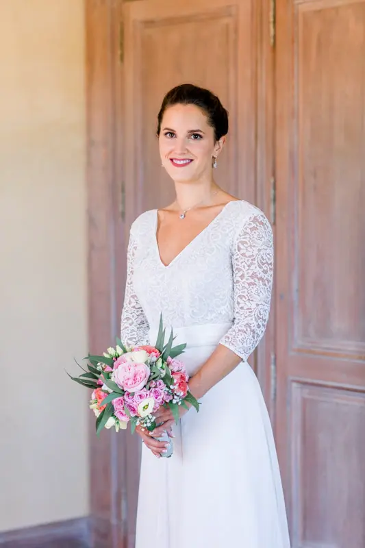 Bride in a lace-sleeved gown in front of a wooden door