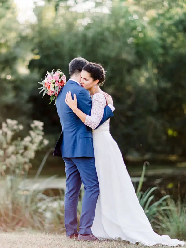 Bride and groom embracing by a pond in the park of Château Giscours