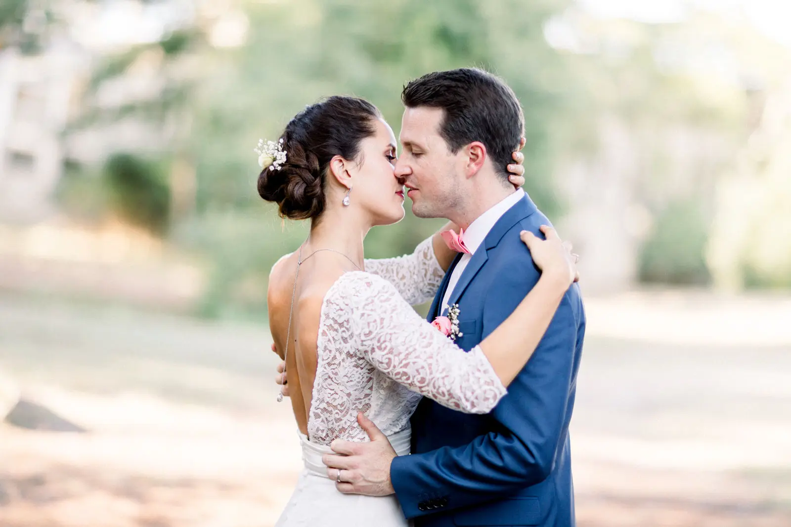 Bride and groom embracing and kissing in the tree-lined château park