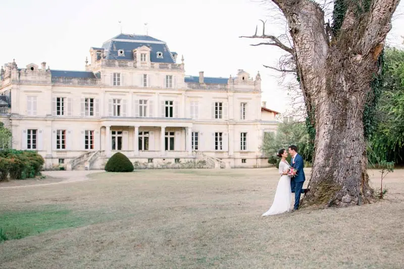 Bride and groom by an old tree facing Château Giscours in the Médoc
