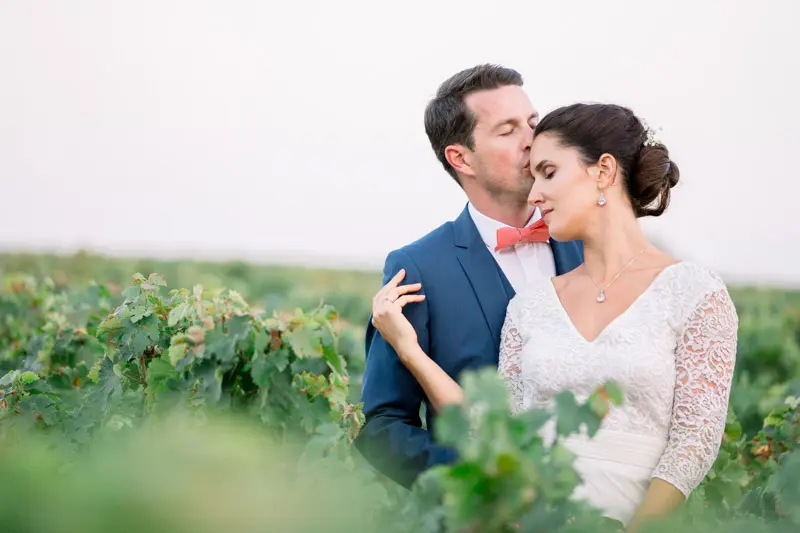 Groom kissing the bride's temple among the vines