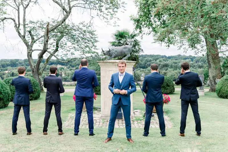 Groom and groomsmen in blue suits seen from behind around a statue