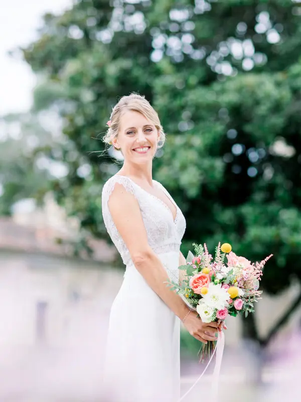 Marion smiling with her colourful bouquet in the château grounds