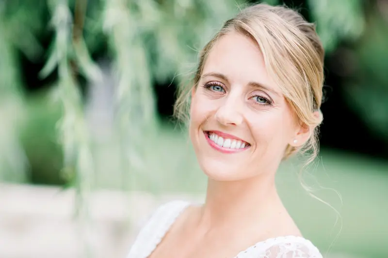 Portrait of the smiling bride beneath willow branches