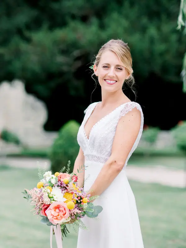 Bride in a lace gown holding her bouquet of vivid flowers
