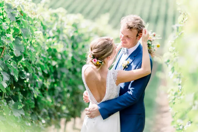 Bride and groom embracing among the vine rows of Château de la Ligne