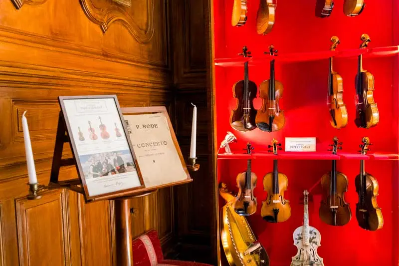 Display of violins against a red backdrop in the Pope's Salon