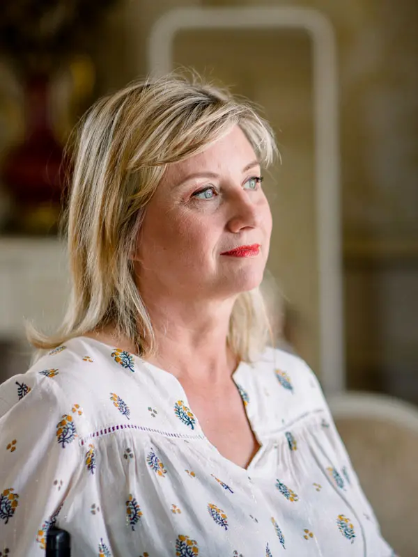 Hélène looking thoughtful in a floral blouse while getting ready