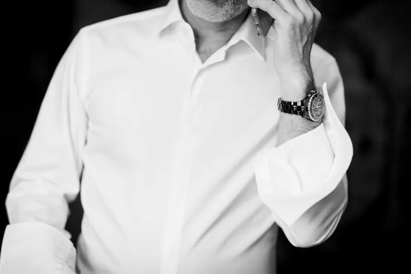 Groom adjusting his white shirt and watch, in black and white