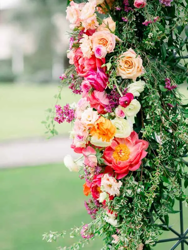 Ceremony arch of coral roses, peonies and ranunculus