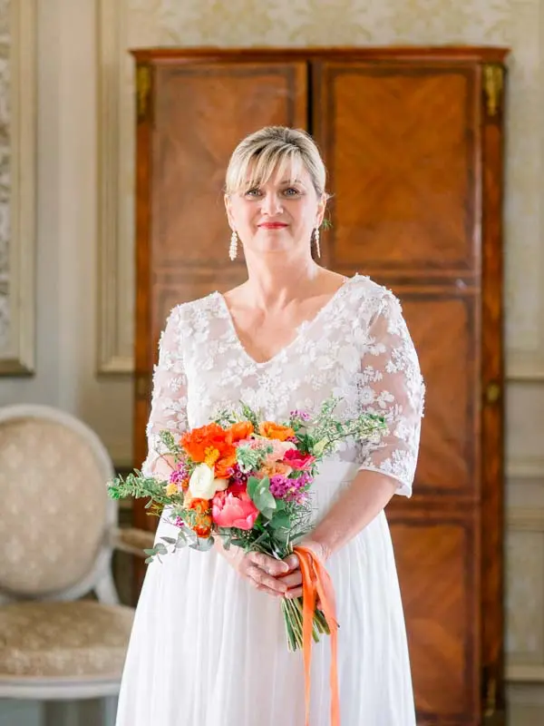 Smiling bride standing before an antique wooden wardrobe