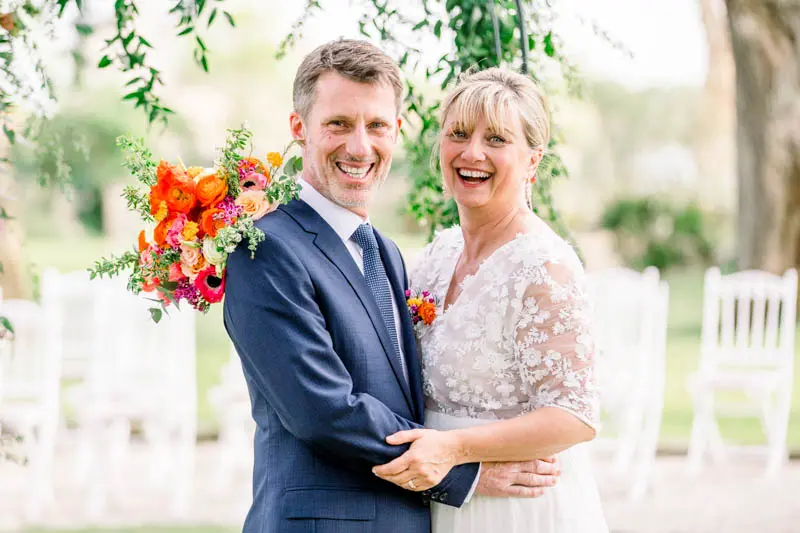 Bride and groom laughing in an embrace beside the white ceremony chairs