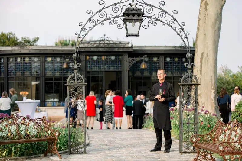 Wedding cocktail hour in front of the orangery and its wrought-iron arch