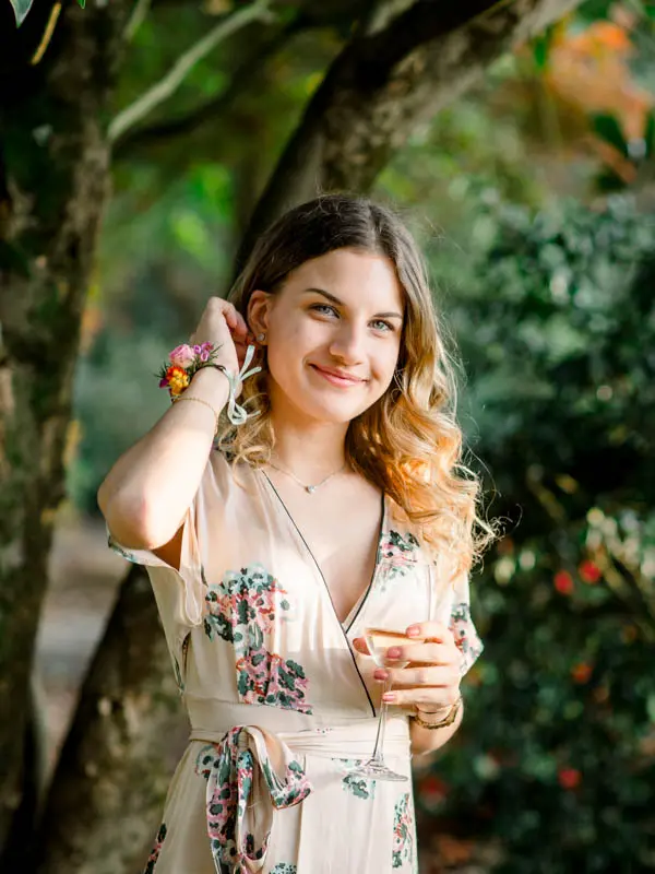 Guest in a floral dress smiling beneath the trees in the grounds