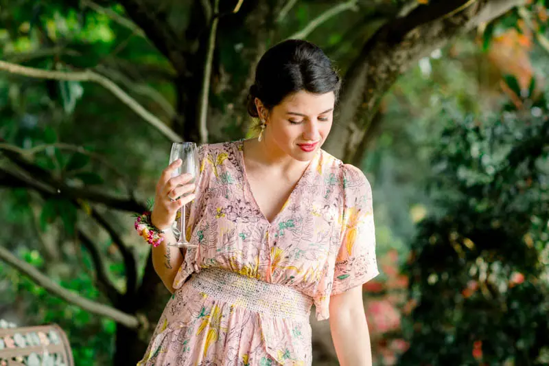 Guest in a floral dress holding a glass of champagne at the cocktail hour
