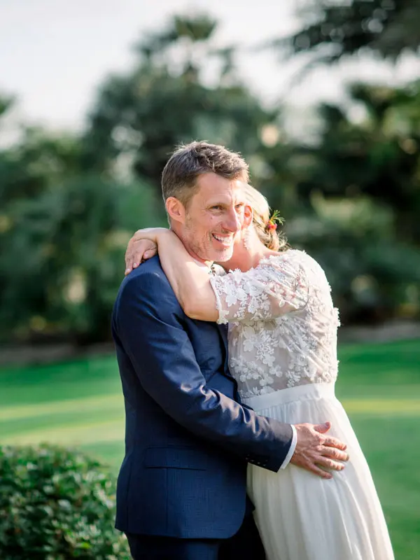 Bride wrapping her arms around the groom on the lawn