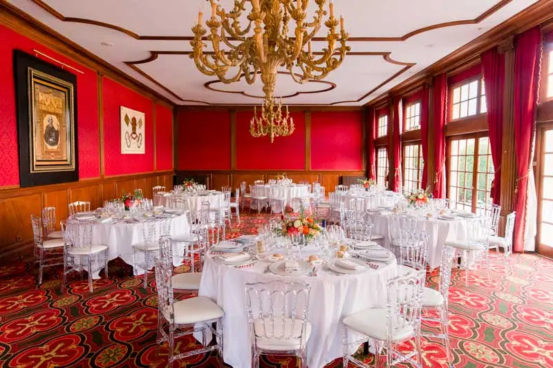 Red reception room with gilded chandelier set for the wedding dinner