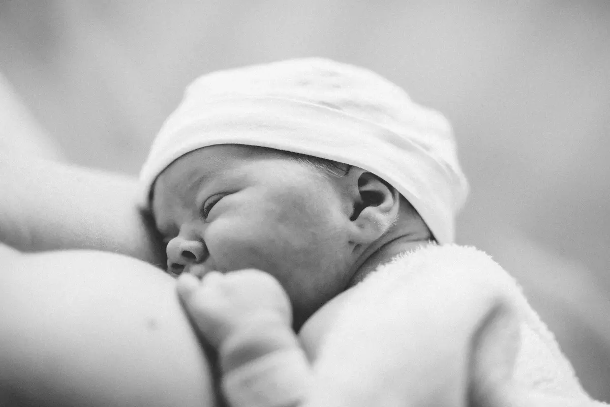 Nouveau-né endormi contre sa maman, photo de naissance en noir et blanc