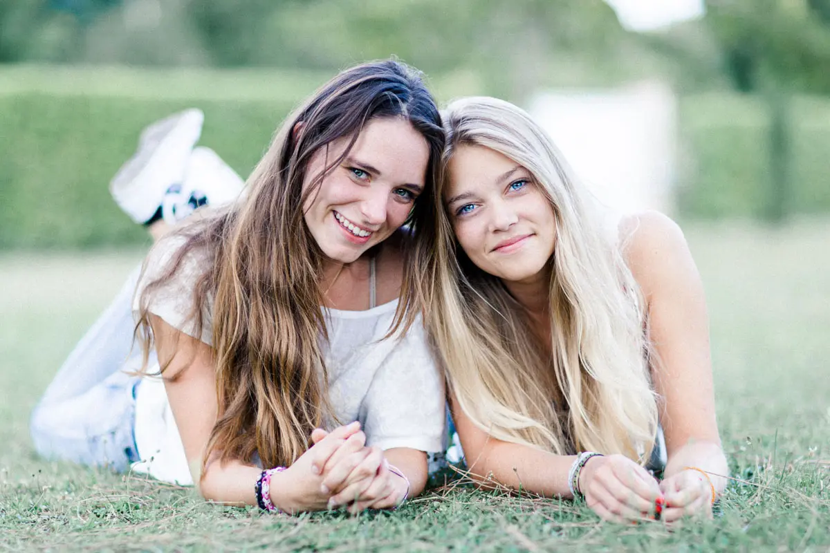Two young women lying on the grass, smiling cheek to cheek