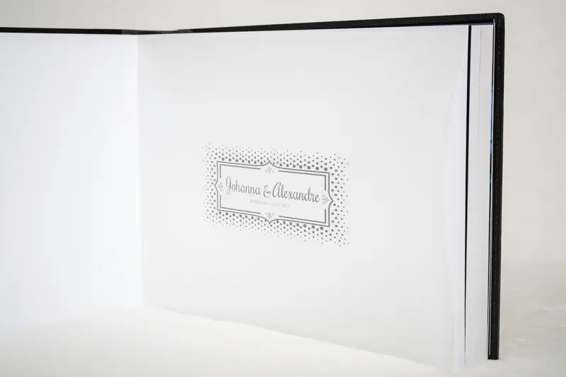 Page de garde blanche ornée des prénoms des mariés dans un cadre gravé