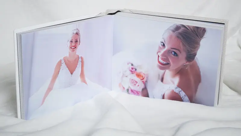 Livre photo ouvert sur deux portraits de la mariée en robe blanche
