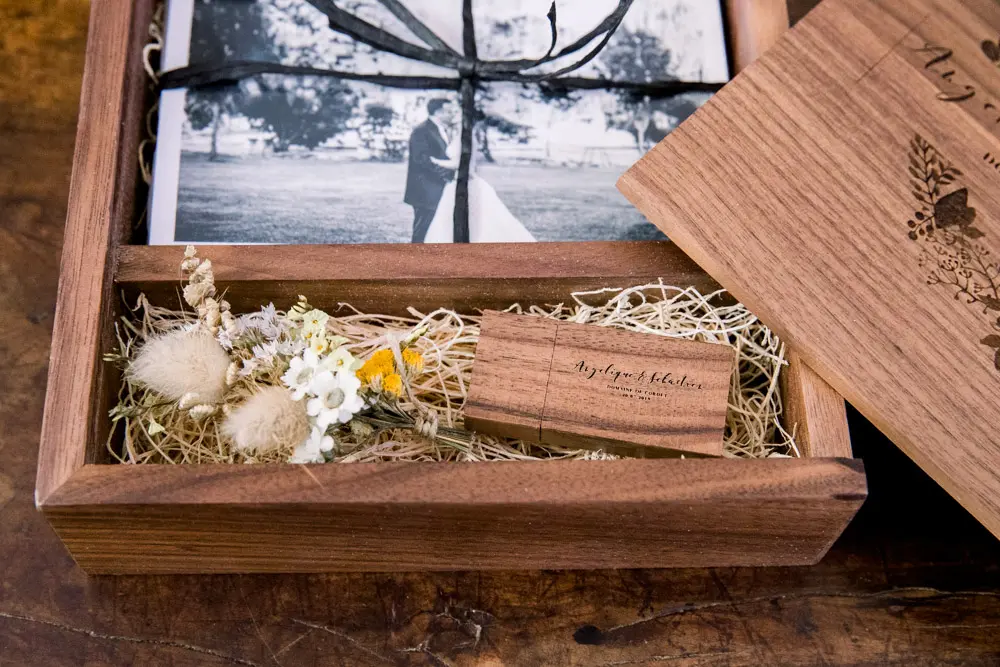 Open wooden box with prints, dried flowers and a wooden USB stick