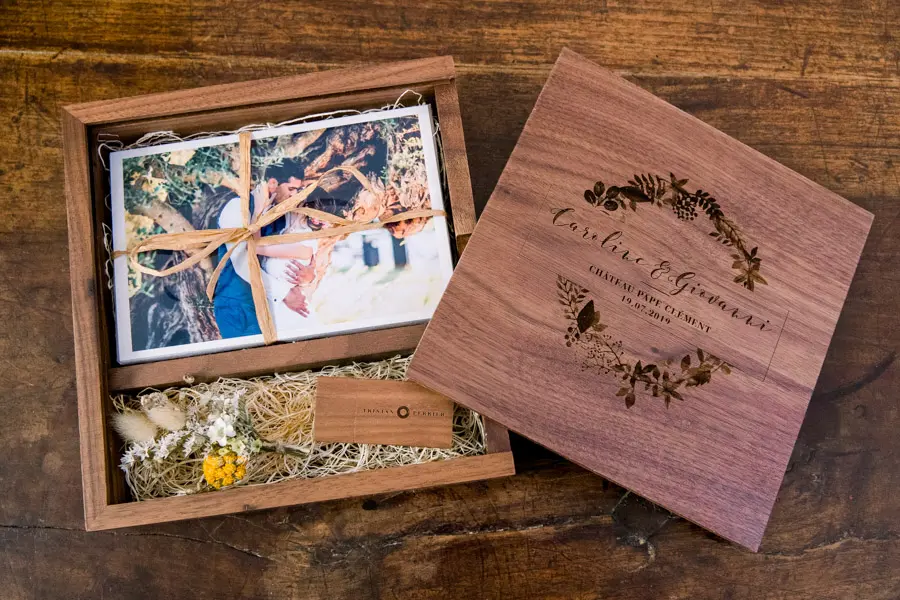 Coffret en bois de noyer ouvert, couvercle gravé posé à côté des tirages