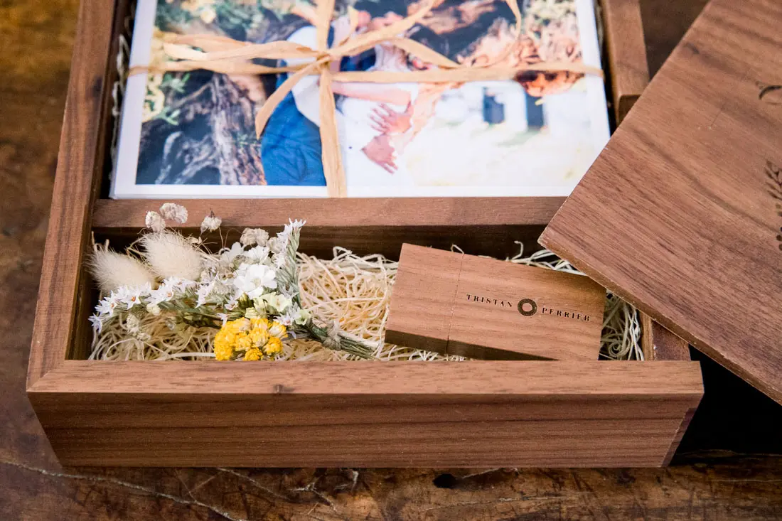Wooden box filled with prints, dried flowers and an engraved USB stick