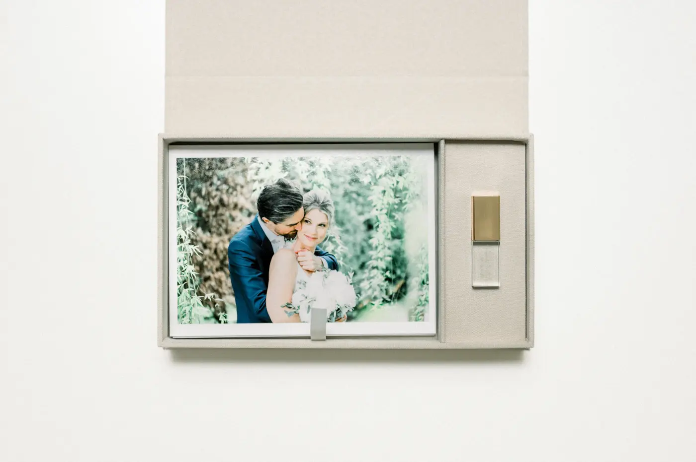 Open linen box with prints of the newlyweds and a USB stick